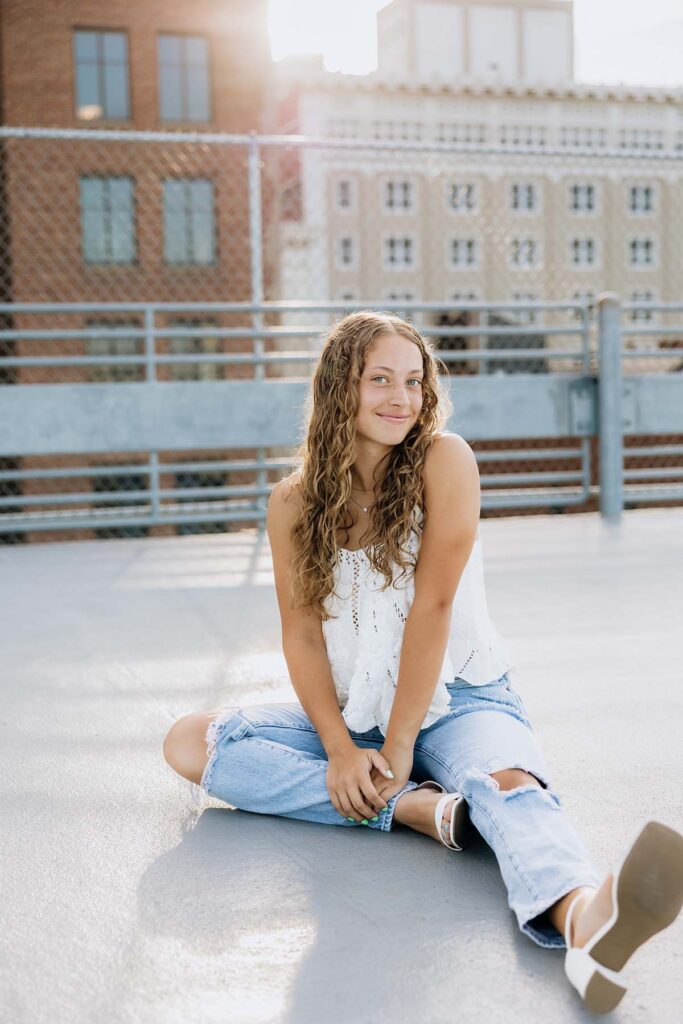 Senior girl sitting on downtown rooftop in casual outfit Lincoln Nebraska photographer