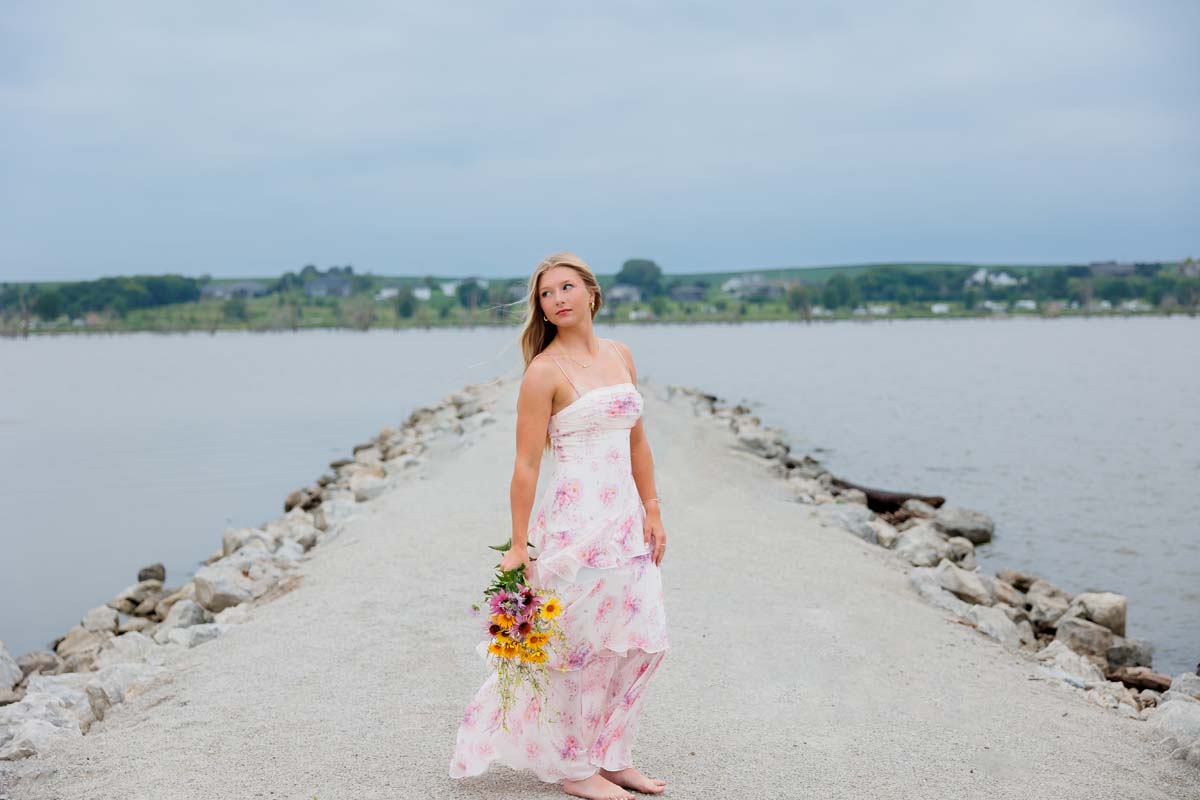 Senior girl in floral maxi dress with bouquet on lake Wanahoo in Wahoo Nebraska senior photographer