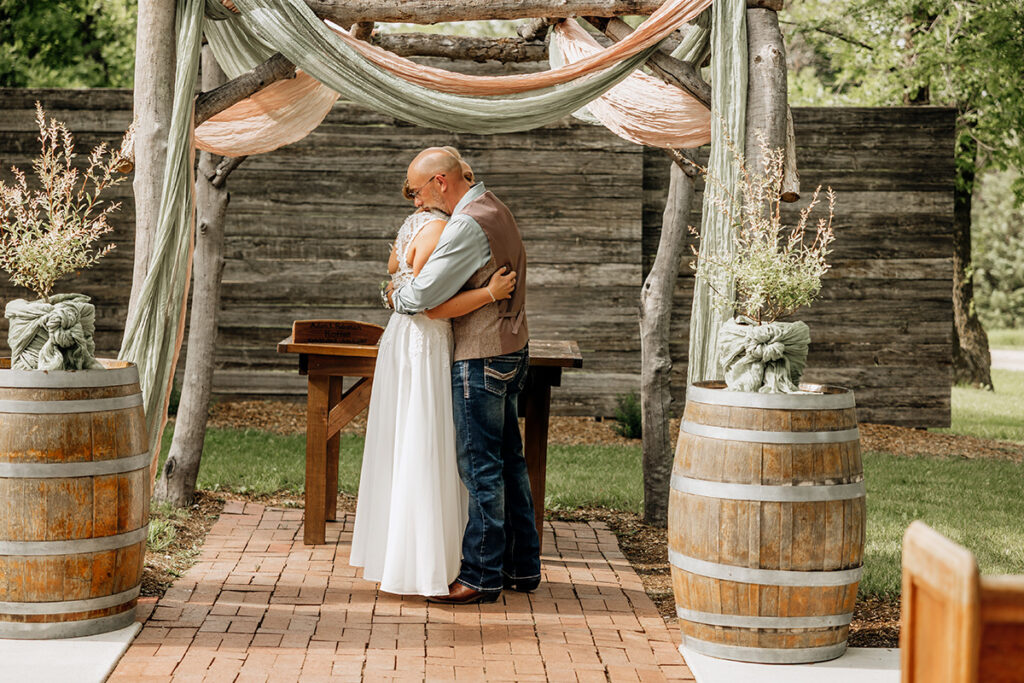 Outdoor wedding ceremony under rustic log arch at Country Pines Lincoln Nebraska