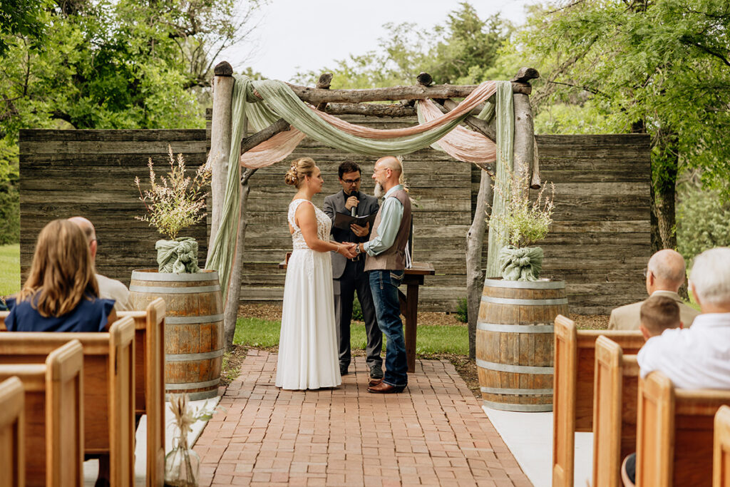 Outdoor wedding ceremony under rustic log arch at Country Pines Lincoln Nebraska
