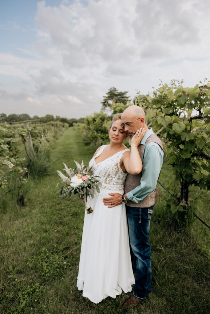 Bride and groom walking hand in hand through vineyard at Country Pines Lincoln Nebraska